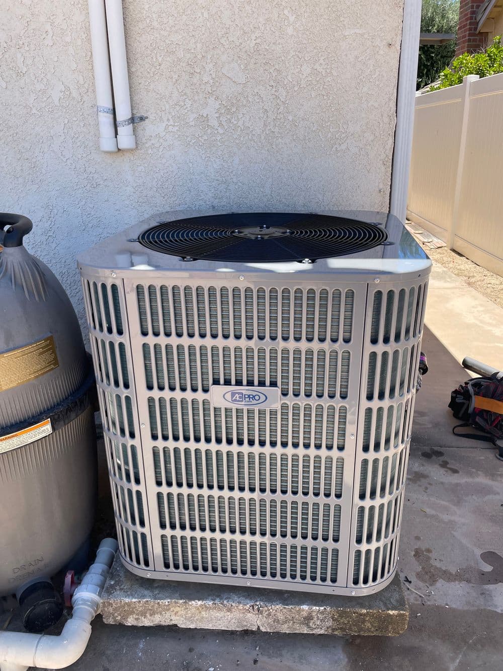 Air conditioning unit installed outside a house, next to a pool equipment. Efficient cooling solution.