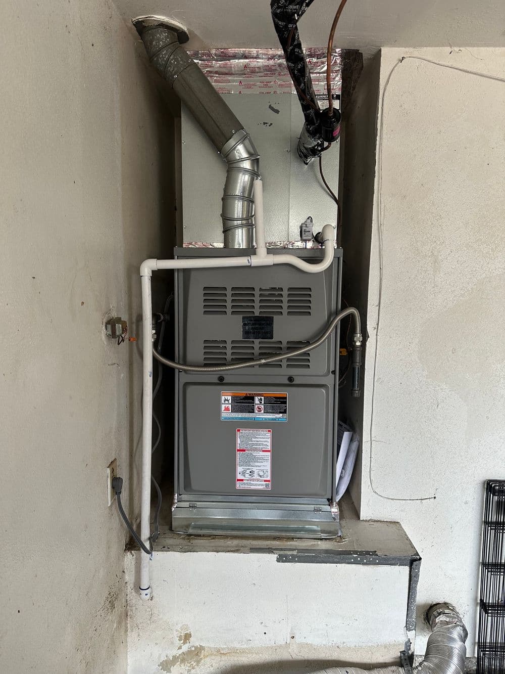 Furnace installation in a residential basement with venting and plumbing details.