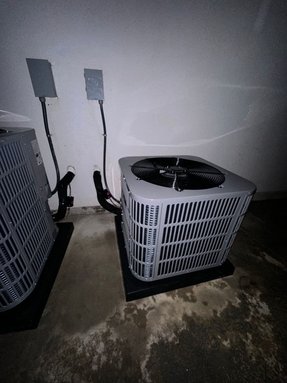 Air conditioning unit installed indoors, gray exterior, mounted on a concrete floor.