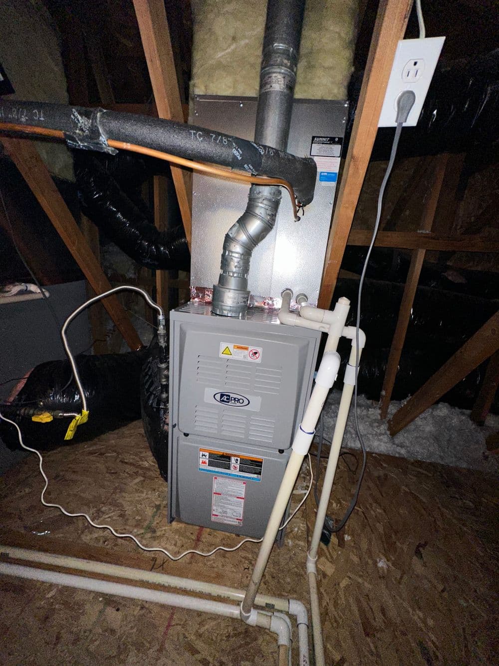 Furnace installation in attic with ductwork and plumbing connections visible.