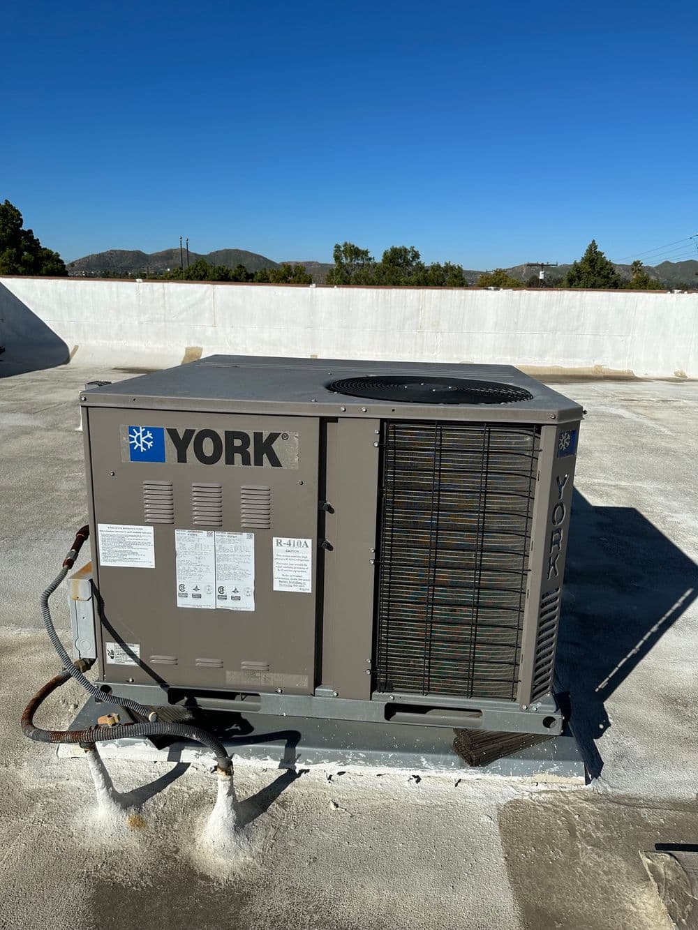York commercial HVAC unit on a flat rooftop with clear blue sky in the background.