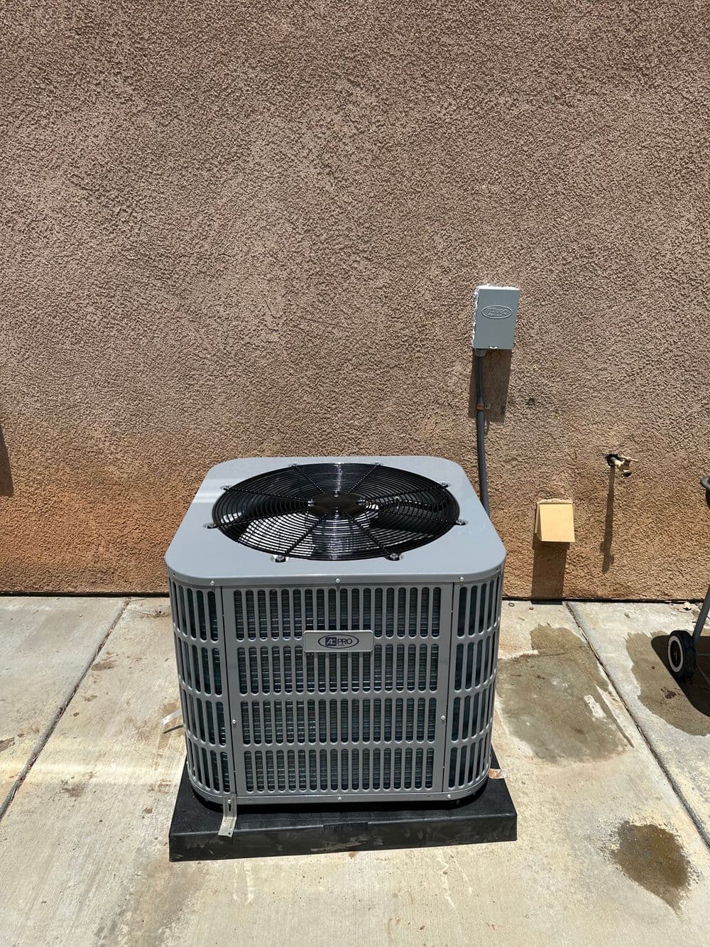 Air conditioning unit installed on concrete slab outside a building.