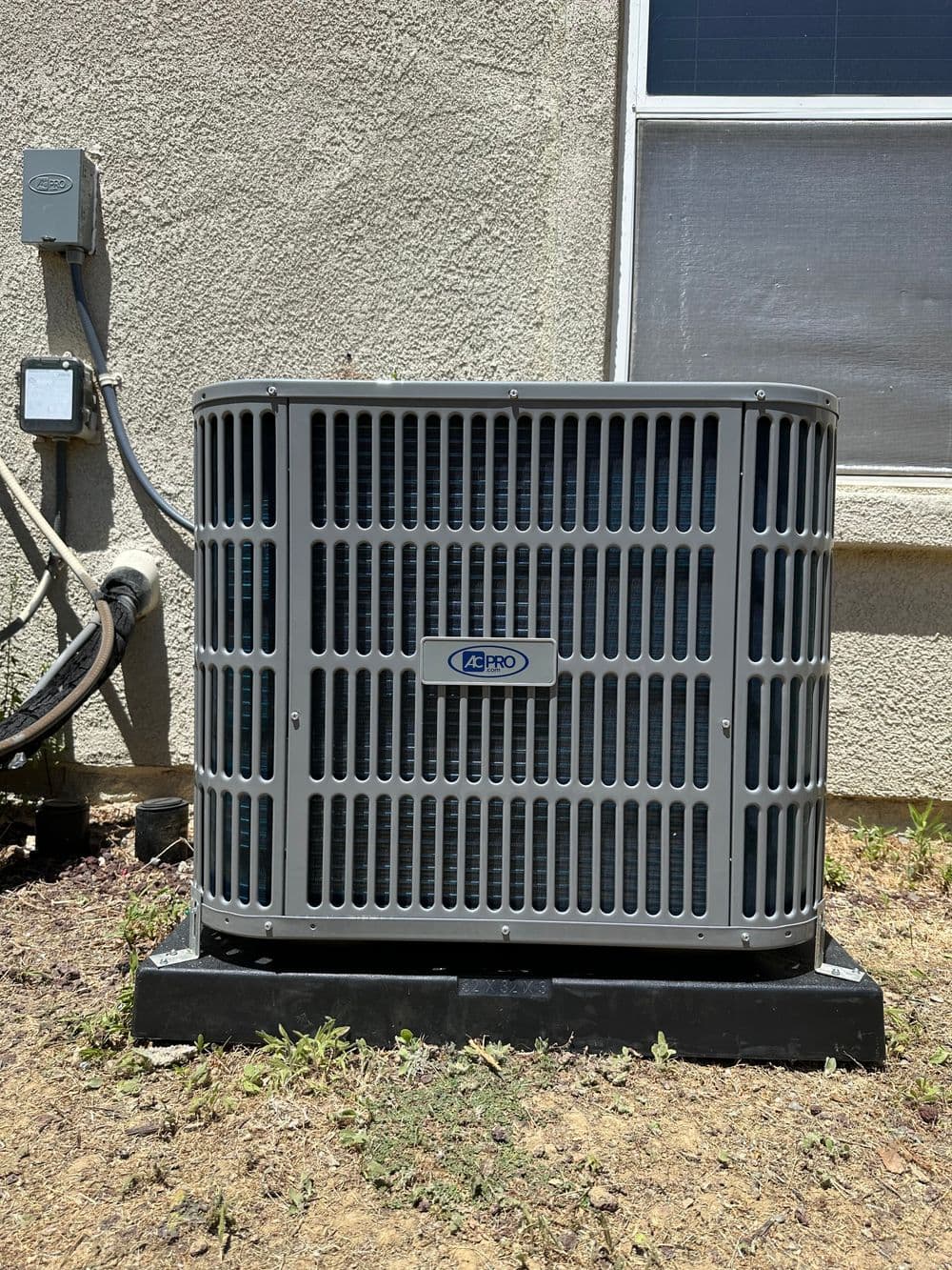 Air conditioning unit installed on grass beside a house, showcasing modern design and efficiency.